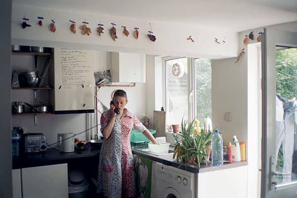 «روث در حال صحبت با تلفن» (۲۰۰۱ – ۲۰۰۲) عکس از نایجل شفران. این عکس بخشی از یک مجموعۀ ادامه‌دار است که این هنرمند در اوایل دهۀ ۱۹۹۰ آغاز نمود. او در این مجموعه از شریک زندگی خود در موقعیت‌های مختلف خانگی عکس می‌گیرد. آخرین کتاب او اتاق‌های تاریک نام دارد.